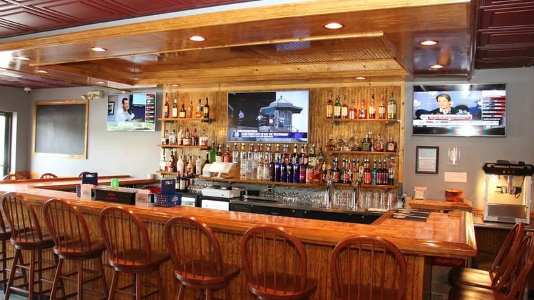 Bar counter lined with chairs and televisions on the bar