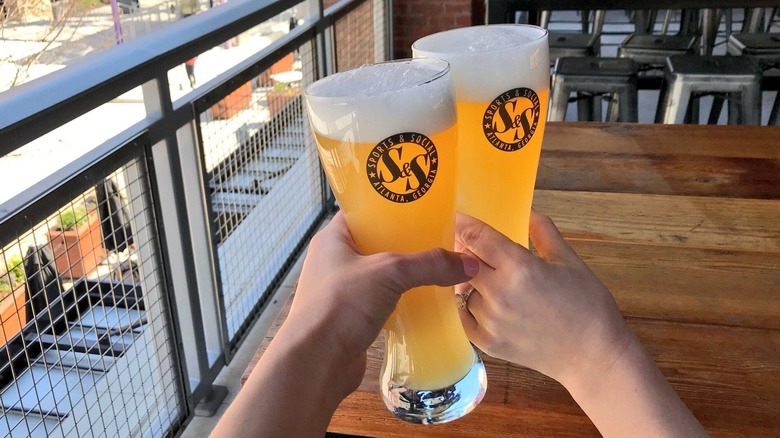 Two hands clinking beer glasses together