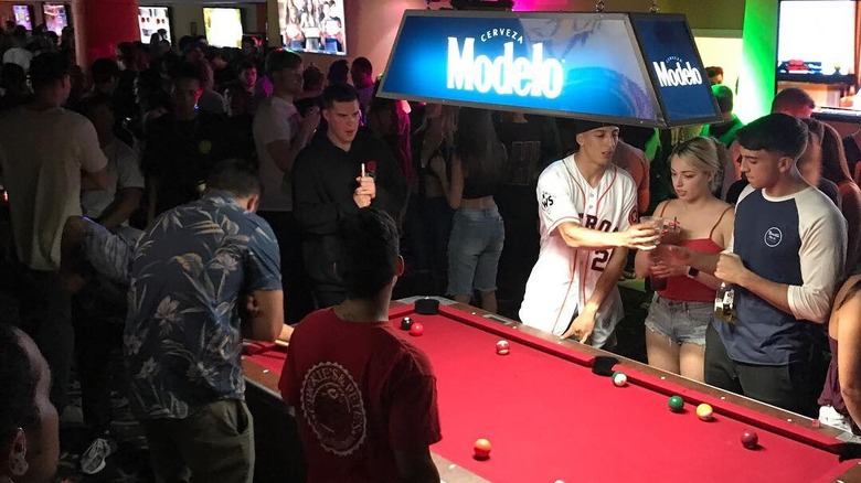 A crowd of people packed around a pool table