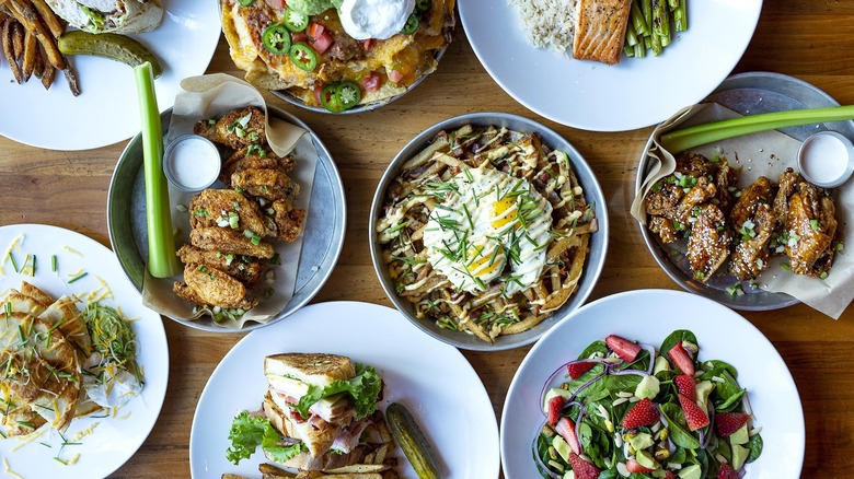 Wooden table with several dishes of food on white china