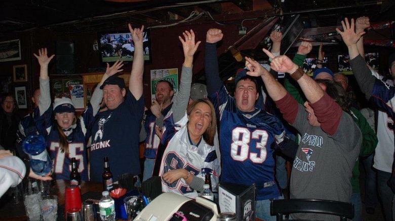 Sports fans in jerseys raising their arms in the air and cheering