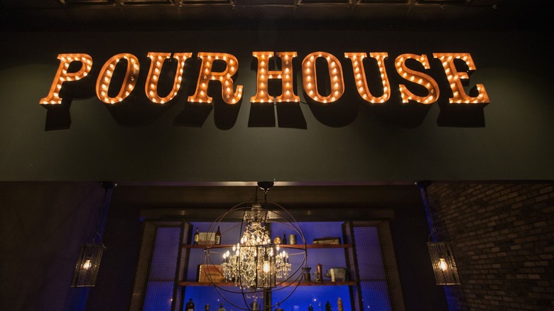 Neon lights that read "Pourhouse" and a chandelier