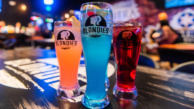 Three glasses of beer on top of a bar counter.