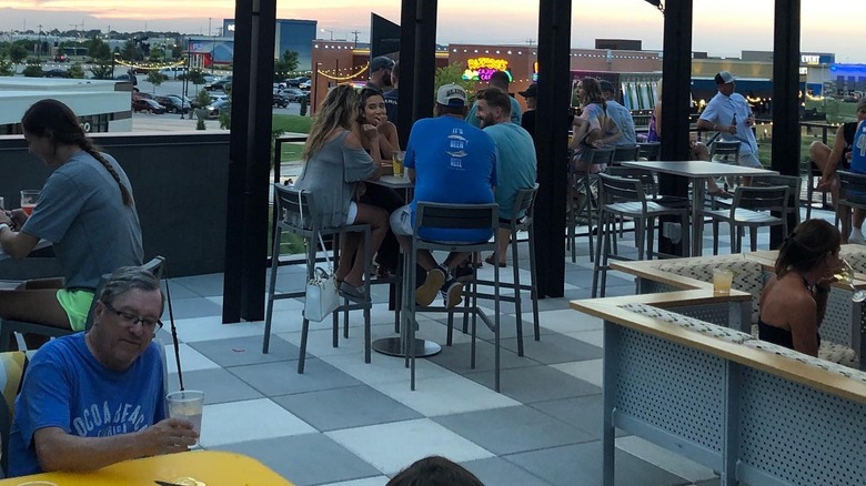 Groups of people sitting on an outdoor patio. 