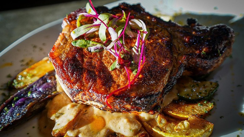 Cast Iron Pan Seared Organic Pork Chop served with Sautéed Zucchini and Summer Squash, Roasted Local Tri Colored Fingerling Potatoes finished in a Red Eye Gravy