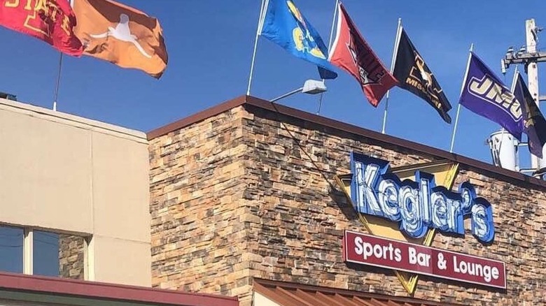 Building decorated with flags of different sport teams and a sign that says, "Kegler's Sports Bar & Lounge."