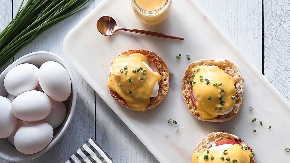 Plate of eggs benedict with raw ingredients  