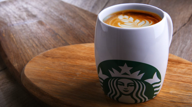 Cappuccino in Starbucks mug on wooden table