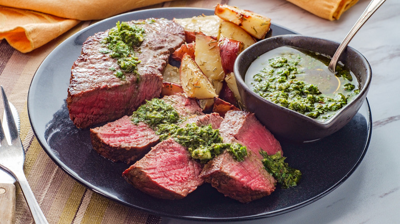 Chimichurri sauce poured over sliced steak