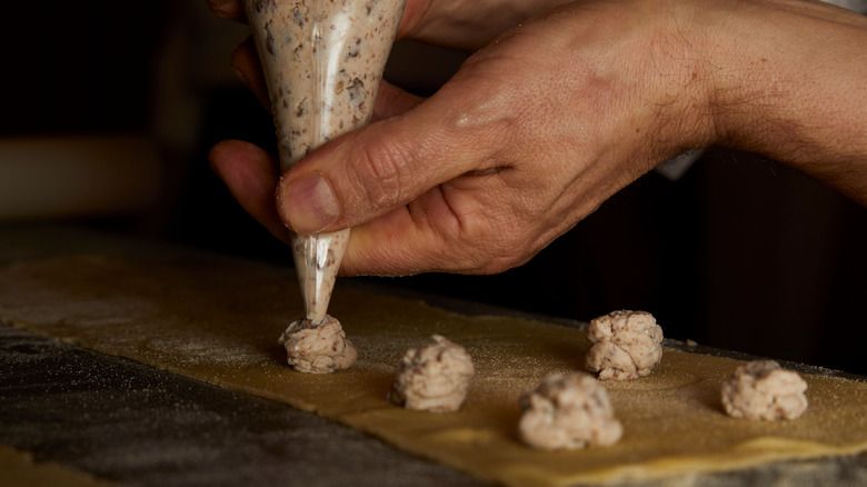 Hand piping chestnut filling into ravioli sheeets