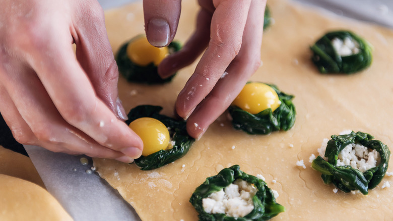 Hands filling and shaping egg yolk ravioli