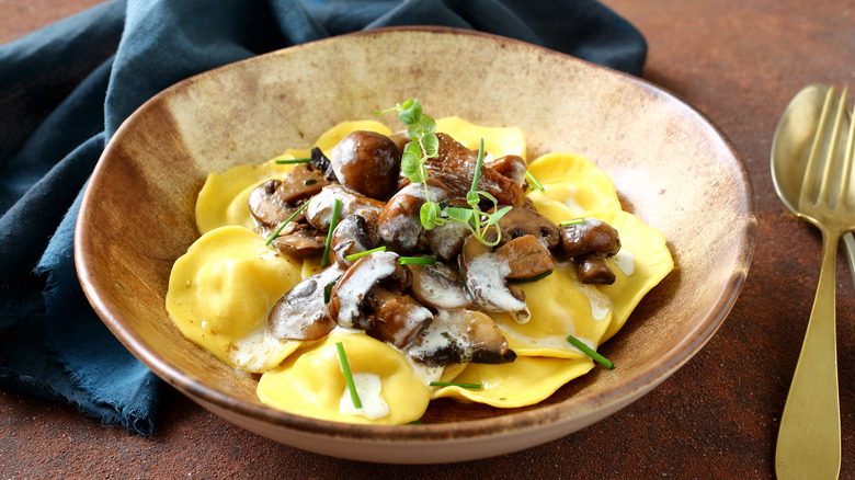 mushroom ravioli topped with mushrooms in wood bowl