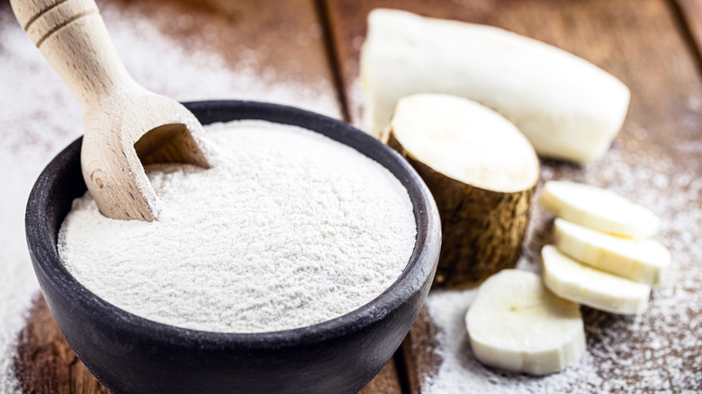 Clay pot with cassava flour next to cassava root 