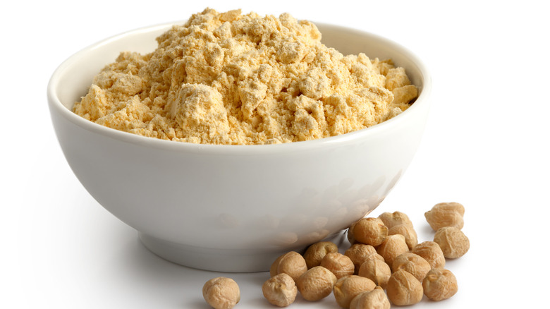 Chickpea flour in white bowl next to whole chickpeas