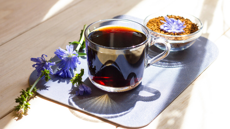 Glass mug of chicory coffee next to flowers