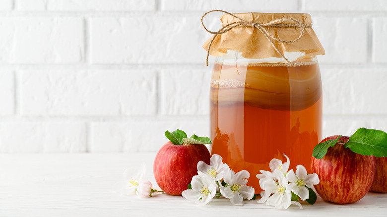 Kombucha in glass jar next to apples