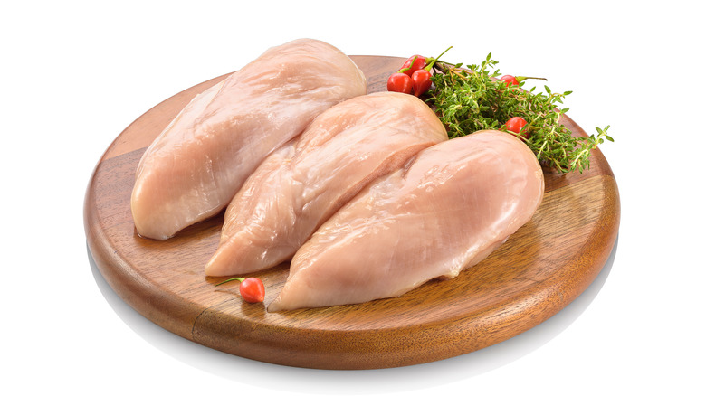 Boneless skinless chicken breast on a round board