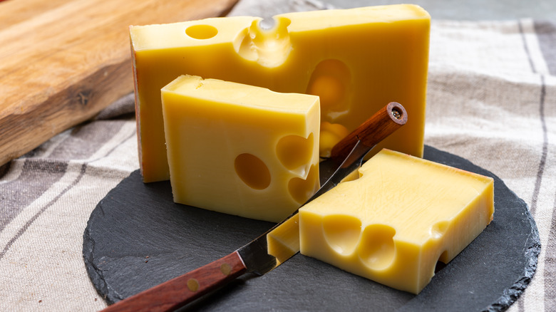 Slices of Swiss Emmental cheese on cutting board