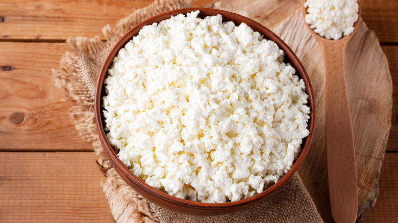 Cottage cheese in wooden bowl next to spoon