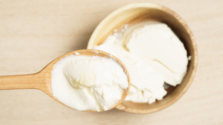 Soft tofu in a wooden spoon with bowl in background