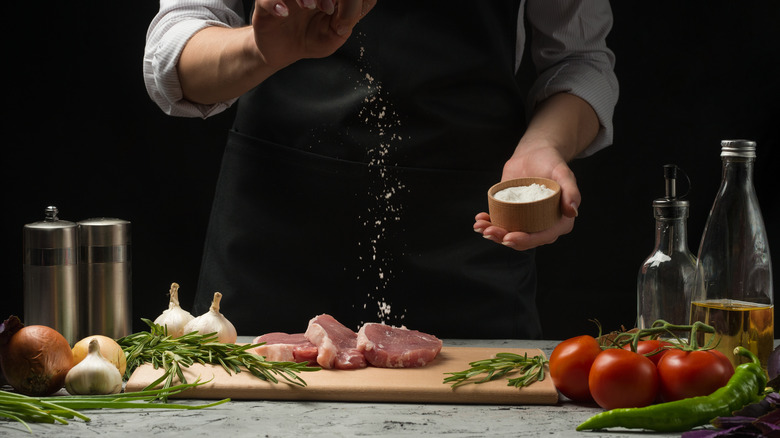 Chef sprinkling onion salt on meat