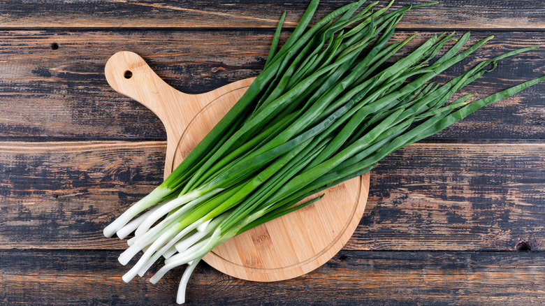 Long scallions on a wooden chopping board