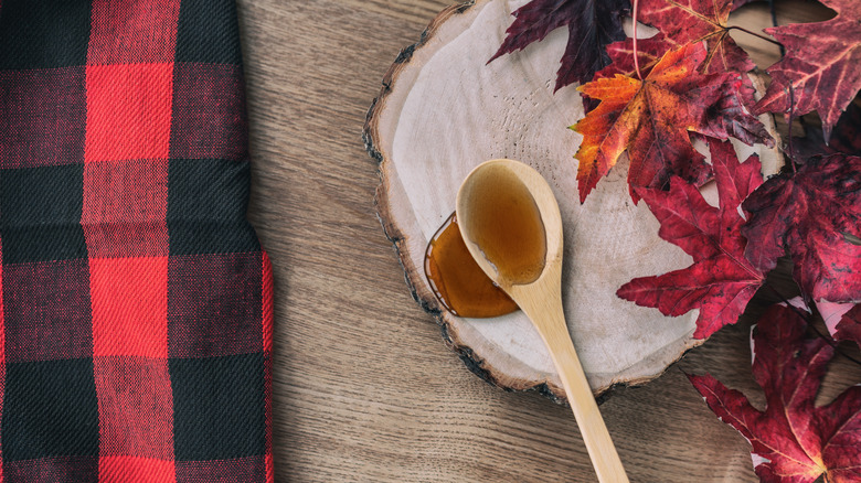 Maple syrup on wood table next to leaves