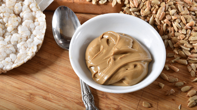 Sunflower butter next to spoon and rice cake