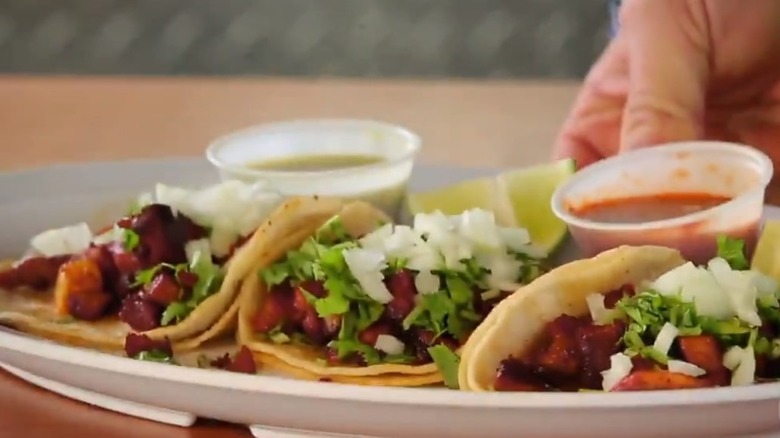 Trio of Al Pastor tacos being served