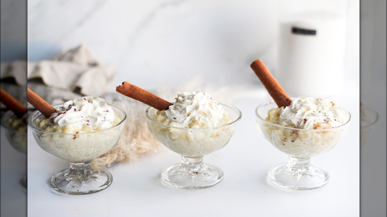 Three cups of rice pudding whipped cream cinnamon sticks