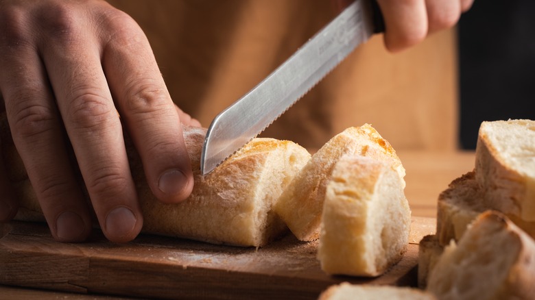 Person cuts bread with serrated knife