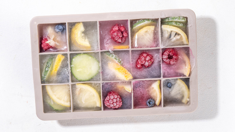 Tray of ice cubes with fruit frozen inside