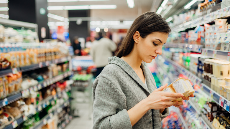 Woman in supermarket reading yogurt packaging