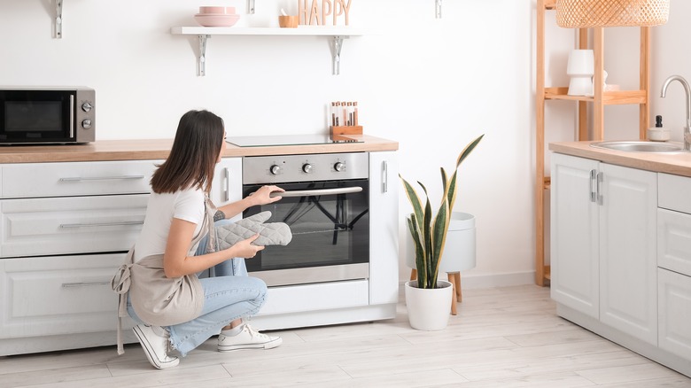 A woman taking a dish out of the oven. 