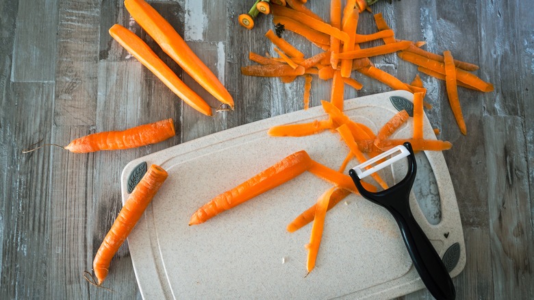 Carrots on a wooden table with a peeler