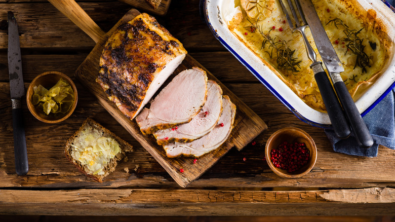 braised pork loin cut into slices on wooden cutting board