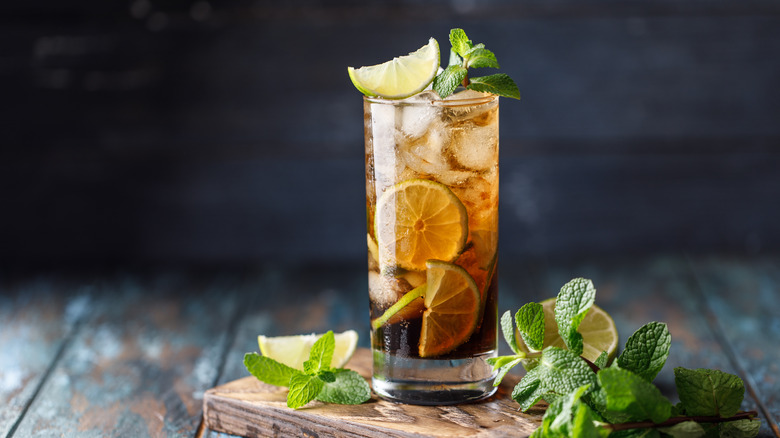 long island iced tea wiht mint and lime on wooden cutting board