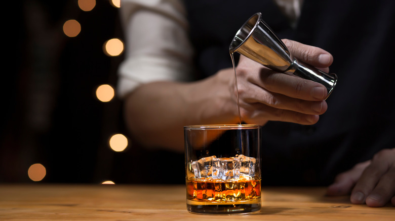 Server pouring whiskey into glass