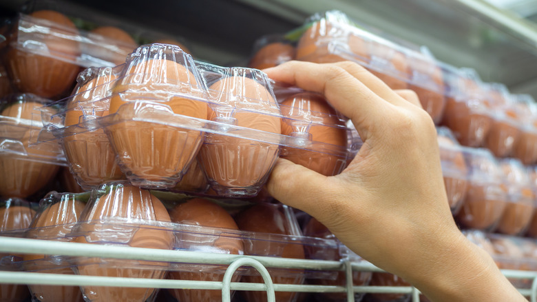 person grabbing clear egg carton