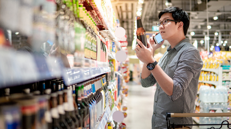 man holding beer and phone