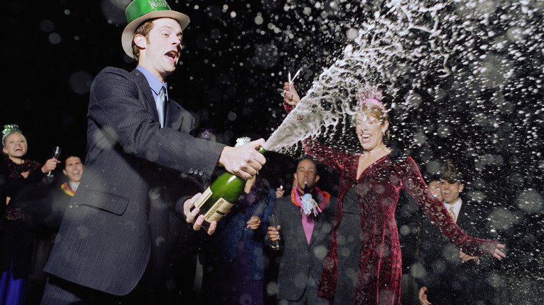 man spraying bottle of champagne