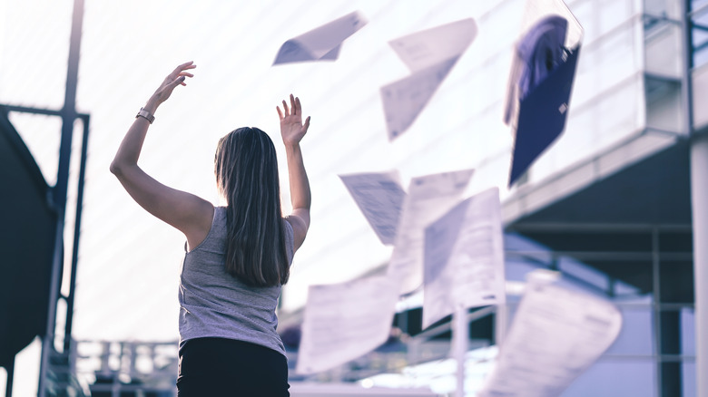 woman throwing papers outside