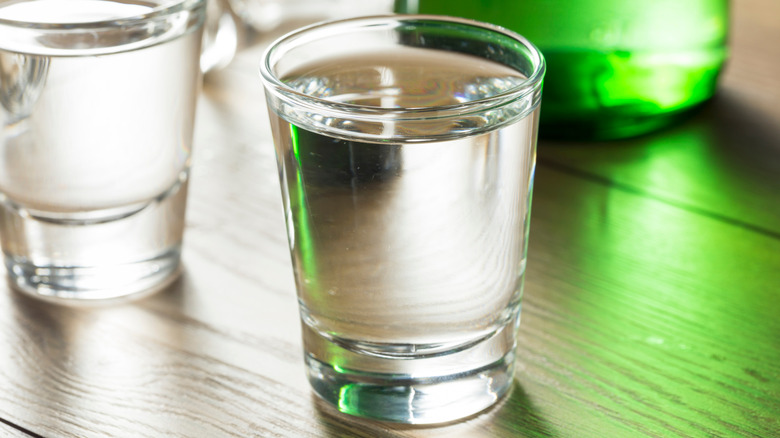 shot glasses of Korean soju with green bottle in background