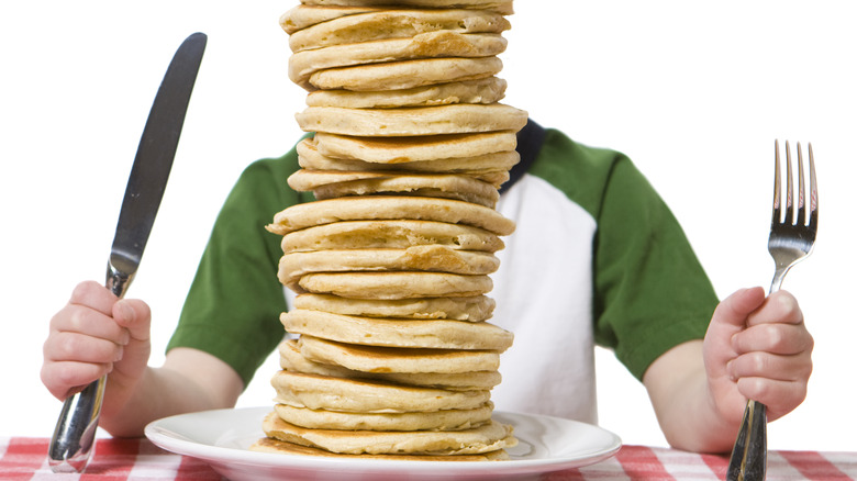 Person hidden behind pancake stack