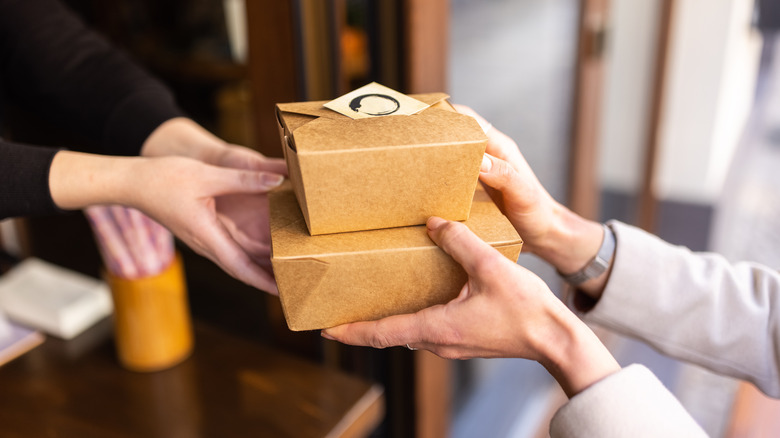 Waitstaff handing containers to customer