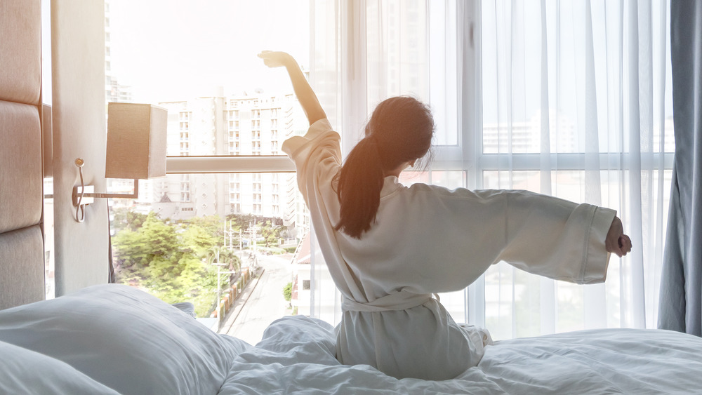 Woman on bed waking up to light 