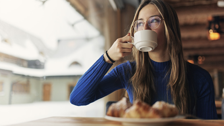 Girl drinking coffee with plate of pastries