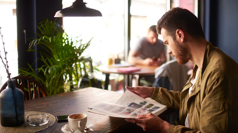 man in coffee shop reading magazine