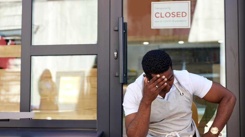 Business owner in front of closed restaurant