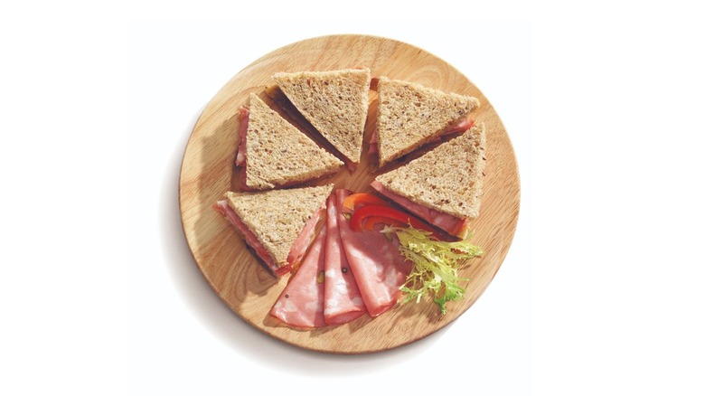 Crustless sandwiches and mortadella on circular cutting board